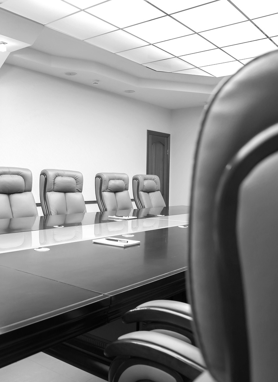 Professional meeting space with a conference style table and multiple armed chairs.